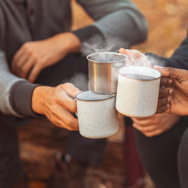 Hands of hikers cheering up with camping cups