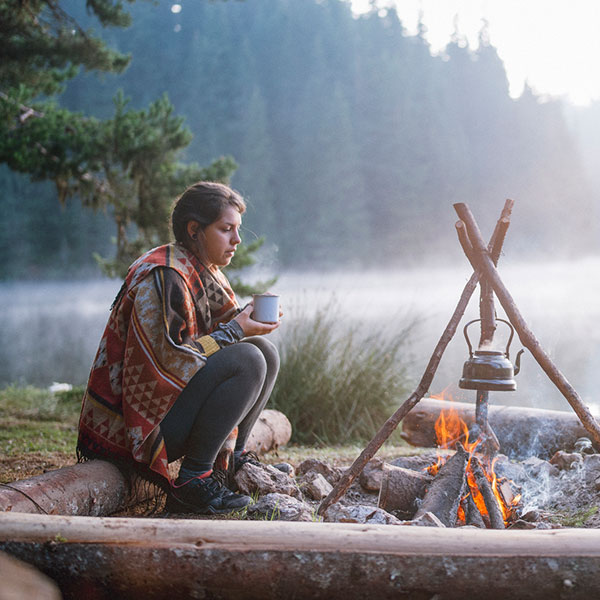 young beautiful woman sitting next to campfire
